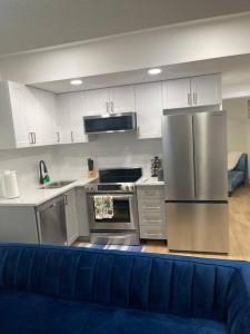 cocina con electrodomésticos de acero inoxidable y sofá azul en Stylish 2 Bedroom suite in SW Edmonton close to Windermere and Edmonton International Airport, en Edmonton