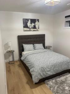 a bedroom with a bed and a picture on the wall at Stylish 2 Bedroom suite in SW Edmonton close to Windermere and Edmonton International Airport in Edmonton