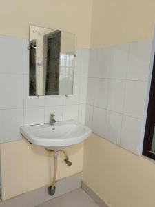 a white bathroom with a sink and a mirror at Shri Gayatri homestay in Ayodhya