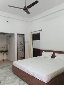 a bedroom with a large white bed with a ceiling fan at Shri Gayatri homestay in Ayodhya
