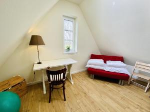 Zimmer im Dachgeschoss mit einem Schreibtisch und einem roten Stuhl in der Unterkunft Haus Milena/Jule in Warnemünde