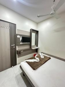 a white room with a bed with a mirror at Rs Regency Hotel in Mumbai