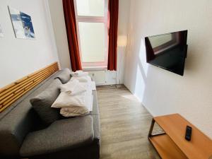 a living room with a couch and a flat screen tv at Haus Stromblick, Zimmer am Strom in Warnemünde