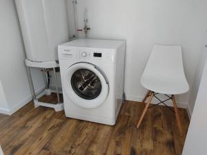 una lavadora y una silla blanca en una habitación en L'institution, en Pont-Hébert