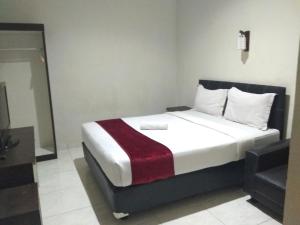 - une chambre dotée d'un lit avec une couverture rouge et blanche dans l'établissement OYO 2991 Satya Homestay, à Makassar