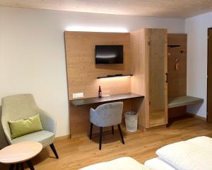 um quarto com uma secretária, uma televisão e uma cadeira em Boutique und Bier Hotel des alpes em Fiesch