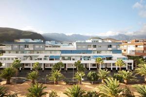 Vistas al mar de un edificio con palmeras y montañas en M y C el Puertito en Pájara