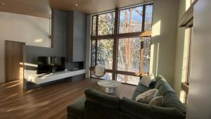 a living room with a couch and a large window at Chalet Infinity by The Hakuba Collection in Hakuba