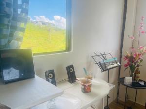 einen Schreibtisch mit einem Laptop, Lautsprechern und einem Fenster in der Unterkunft DOC AZENITH PRESIDENTIAL SUITE in Pagadian