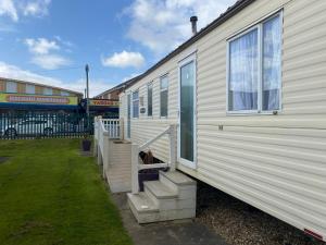 a mobile home with stairs next to a store at Happy Days - Beachfields 370 in Chapel Saint Leonards