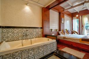 uma casa de banho com banheira e uma cama num quarto em Aqua Marina Beach Cottages em Calangute