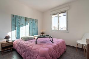 een slaapkamer met een roze bed en een tafel. bij ARES - Vue Mer in Le Grau-dʼAgde