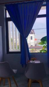 a window with a blue curtain and two chairs at Ngọc Nga Hotel in Phan Rang–Tháp Chàm