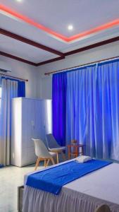 a bedroom with blue curtains and a bed and chairs at Ngọc Nga Hotel in Phan Rang–Tháp Chàm