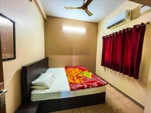 ein kleines Zimmer mit einem Bett mit roten Vorhängen in der Unterkunft Royal Castle Residency in Puducherry