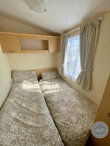 a small room with two beds and a window at Happy Days - Beachfields 370 in Chapel Saint Leonards