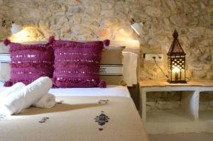 a bedroom with a bed with purple pillows and a table at Peralta Villas Boutique Adults Only in Renau