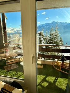 a sliding glass door with a view of a snowy mountain at Vue imprenable sur les Alpes et Parking privé gratuit in Crans-Montana