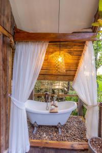 y baño con bañera y cortinas. en Nakhao Cottage, en Ban Wat Tan