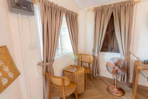 a room with two windows and a table and chairs at Nakhao Cottage in Ban Wat Tan