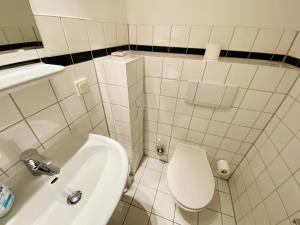 a white bathroom with a toilet and a sink at Landhaus Immenbarg, Seeteufel in Warnemünde