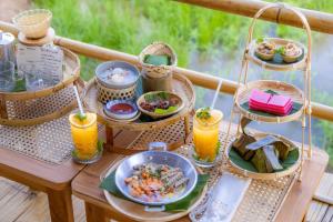 a table with plates of food and glasses of orange juice at Nakhao Cottage in Ban Wat Tan