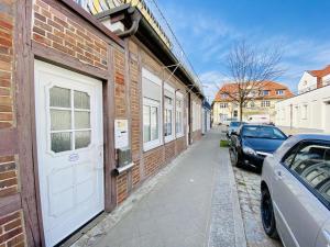 a brick building with a white door and cars parked on a street at Fewo Leuchtturm, ca 200m z. Strand in Warnemünde