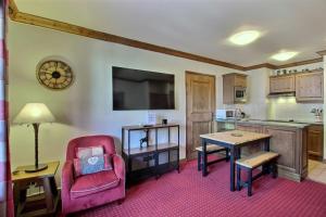 a living room with a red chair and a kitchen at ARC 1950 - Appartement cosy et chaleureux - Sauna, Hammam, Jacuzzi, Piscine in Arc 1950