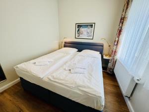 Schlafzimmer mit einem Bett mit weißer Bettwäsche in der Unterkunft Mole in Warnemünde