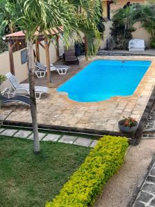 a swimming pool with a palm tree next to a house at Villa santa avec piscine et jardin in Pointe aux Piments