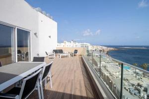 een balkon met een tafel en stoelen en de oceaan bij Seafront Penthouse in St Paul's Bay