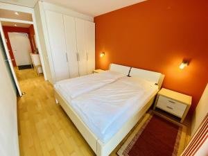 ein Schlafzimmer mit einem weißen Bett und einer orangefarbenen Wand in der Unterkunft Residenz/Koralle in Warnemünde