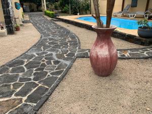 um vaso vermelho sentado no chão ao lado de uma piscina em Villa santa avec piscine et jardin em Pointe aux Piments