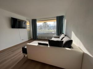 a living room with a white couch and a large window at Frisch renovierte Ferienwohnung in Oberstaufen