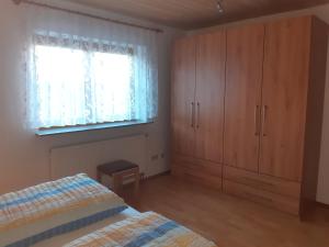 1 dormitorio con cama, armarios de madera y ventana en Ferienwohnung Lechleiter, en Kappelrodeck