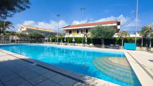 a swimming pool with blue water in front of a building at Le Ville della Contea -Vacation rentals in Mascali