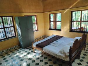 Chithira Homestay (Kerala traditional mud house) في Kodali: غرفة نوم مع سرير في غرفة مع نوافذ