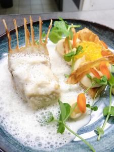 a plate of food with a piece of fish and vegetables at Auberge de Mourjou in Mourjou