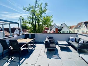een patio met een tafel en stoelen op een dak bij Sonnenschein, direkt am Alten Strom in Warnemünde