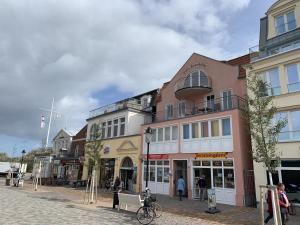 um grupo de edifícios em uma rua com pessoas andando em Sonnendeck, direkt am Leuchtturm em Warnemünde