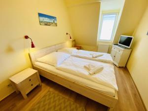 a bedroom with a large white bed and a television at Sonnendeck, direkt am Leuchtturm in Warnemünde