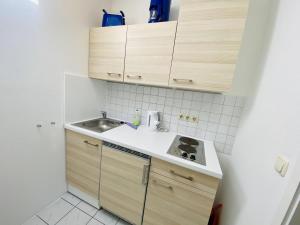 eine kleine Küche mit Holzschränken und einem Waschbecken in der Unterkunft Sterne in Warnemünde
