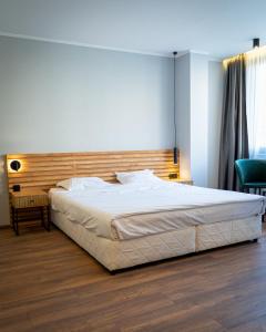 a bedroom with a large bed with a wooden headboard at Family Hotel Pak Tam in Karlovo