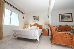 a bedroom with a bed and a chair at E Solo Aruba Apartments in Oranjestad