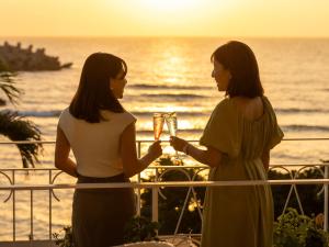 読谷村にある海のテラスよみたん都屋の二人の女性がワインを飲みながらバルコニーに立っている