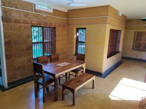 - une salle à manger avec une table et des chaises en bois dans l'établissement Chithira Homestay (Kerala traditional mud house), à Kodali
