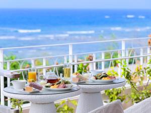 een tafel met borden eten op een balkon met uitzicht op de oceaan bij Umi No Terrace Yomitan Toya in Yomitan