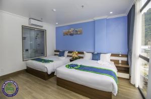 1 dormitorio con 2 camas y pared azul en CHÂN TRỜI MỚI -NEW HORIZON HOTEL, en Cat Ba