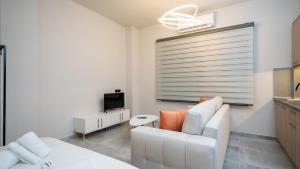 sala de estar con sofá blanco y TV en Tsikaris Guesthouse en Kalambaka