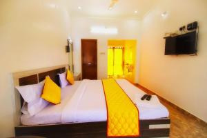 ein Schlafzimmer mit einem großen Bett mit gelben Kissen in der Unterkunft Leo Inn in Yercaud